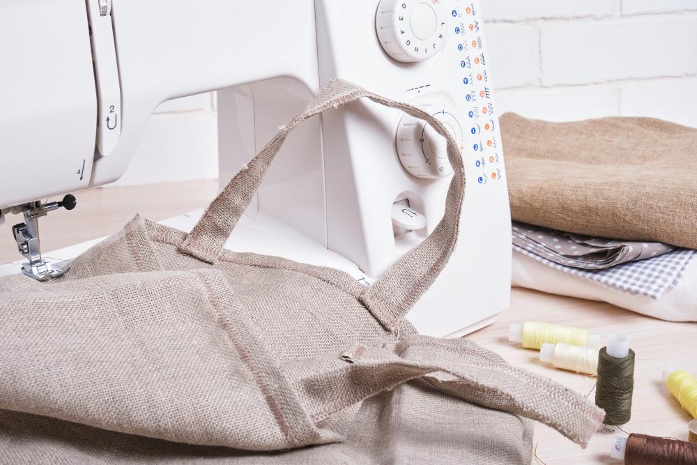 Linen tote bag with handles being sewn on a white sewing machine