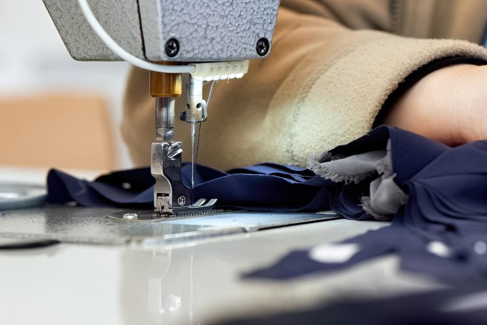 Presser foot holding navy fabric under a sewing machine needle